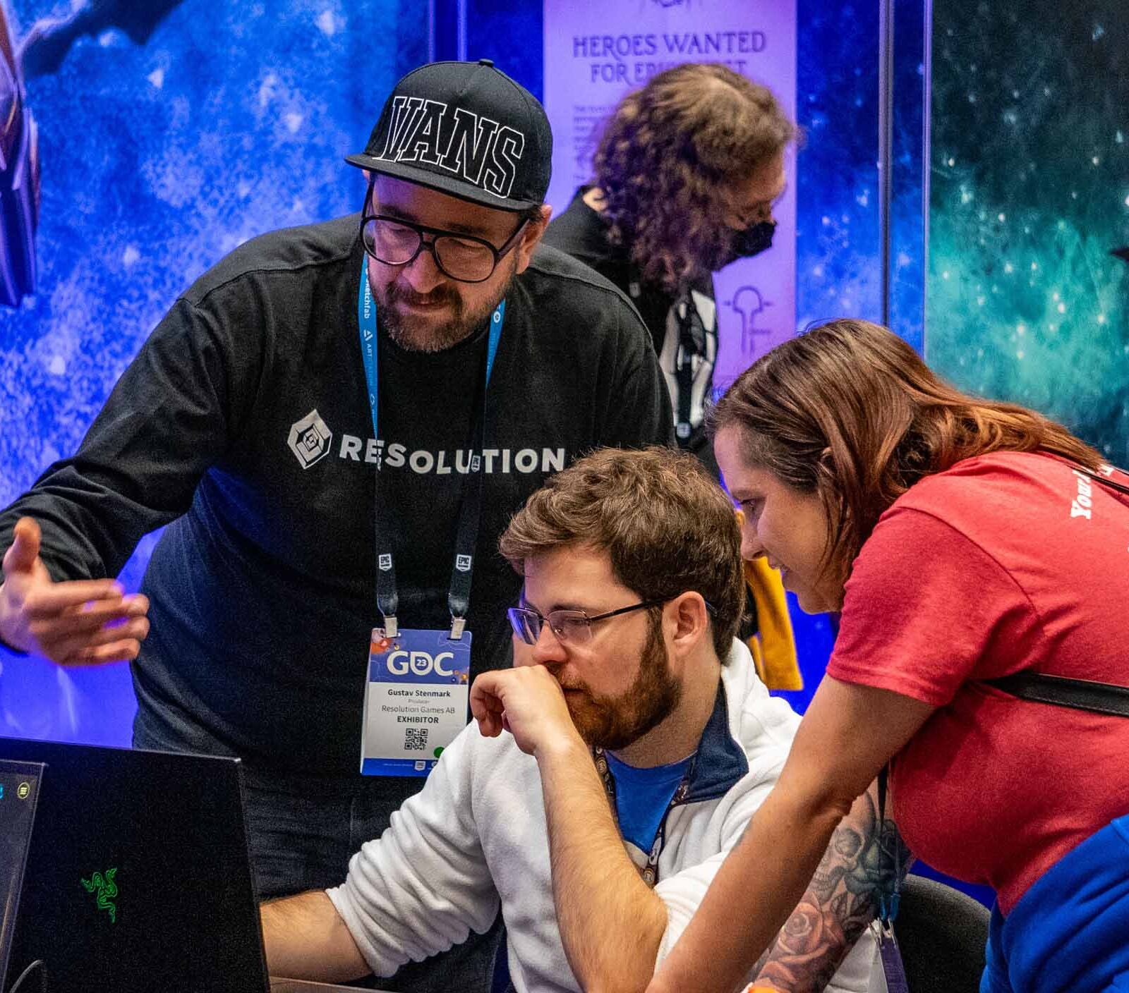 Students and conference members looking at a computer screen against a vibrant and bright background