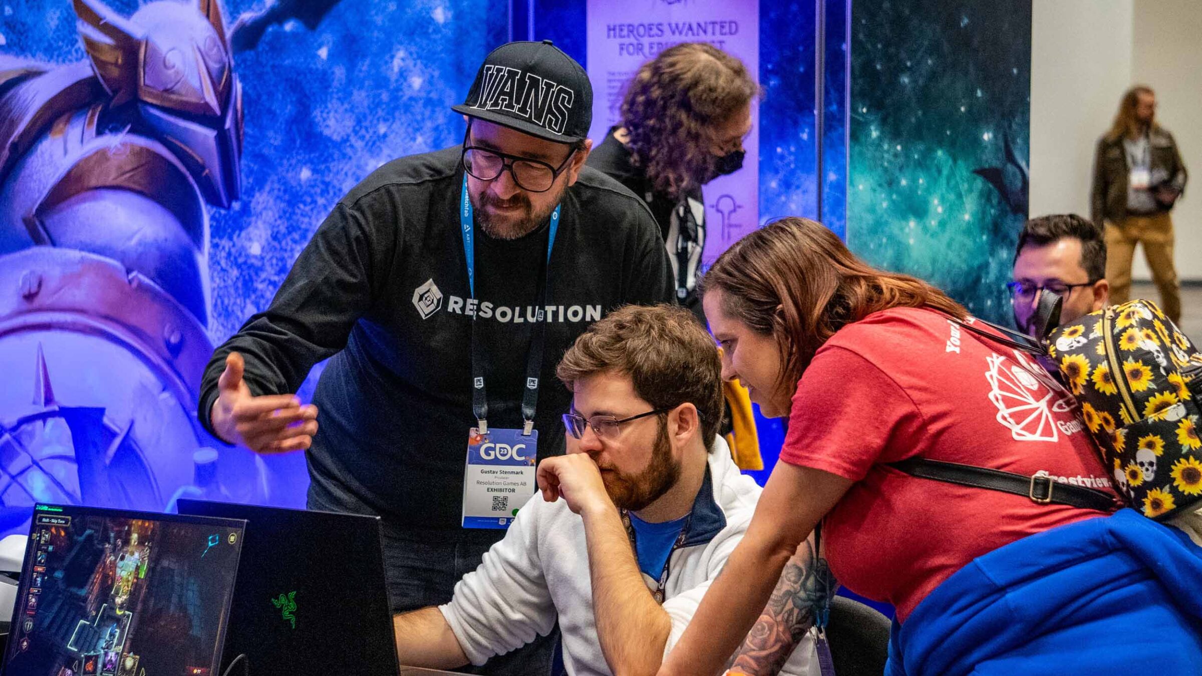 Students and conference members looking at a computer screen against a vibrant and bright background