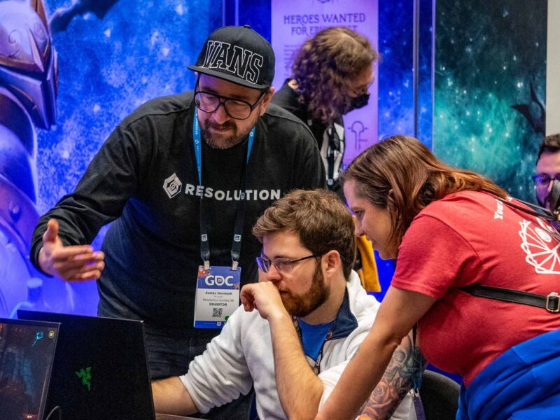 Students and conference members looking at a computer screen against a vibrant and bright background
