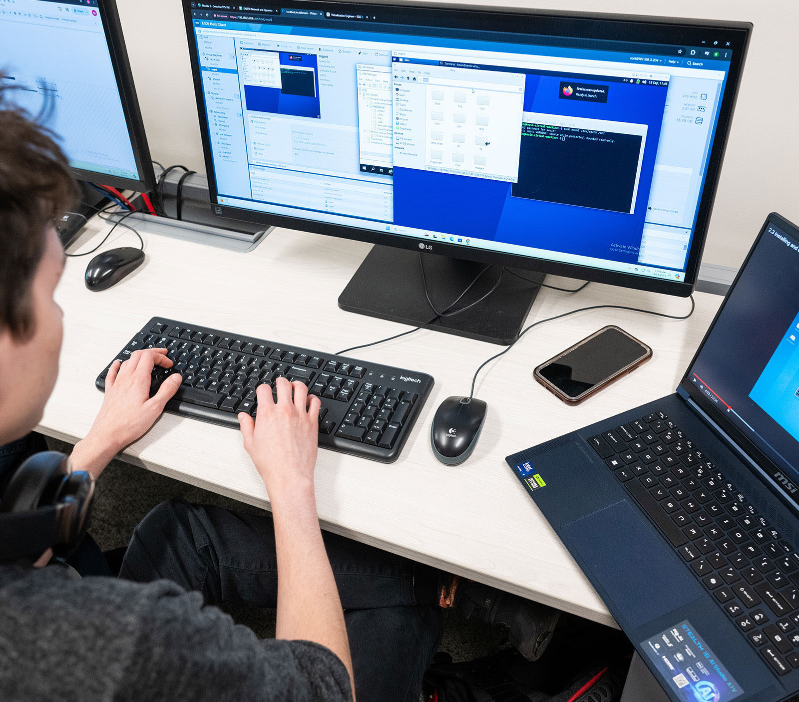 student using multiple computers to code in a computer lab on campus