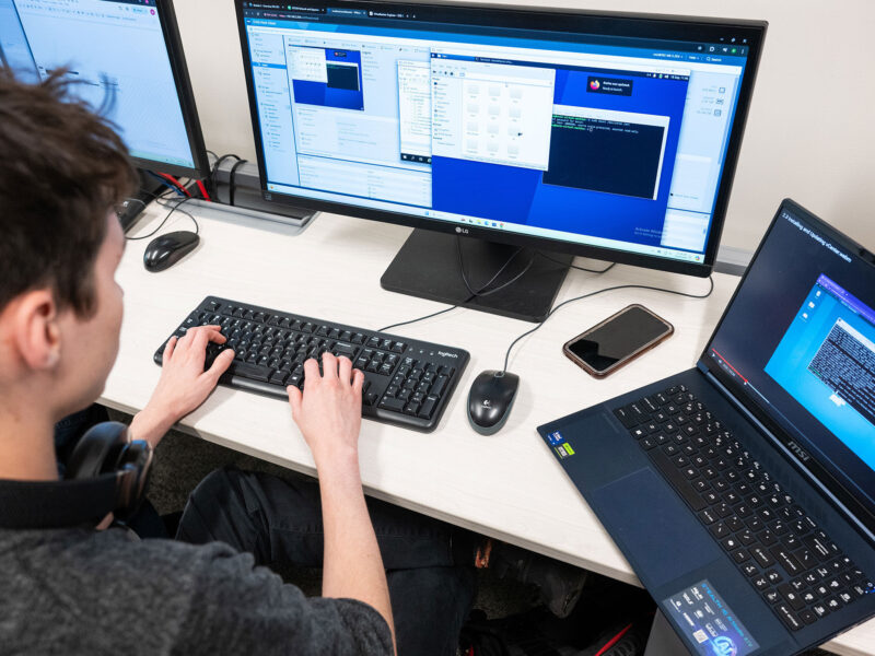student using multiple computers to code in a computer lab on campus