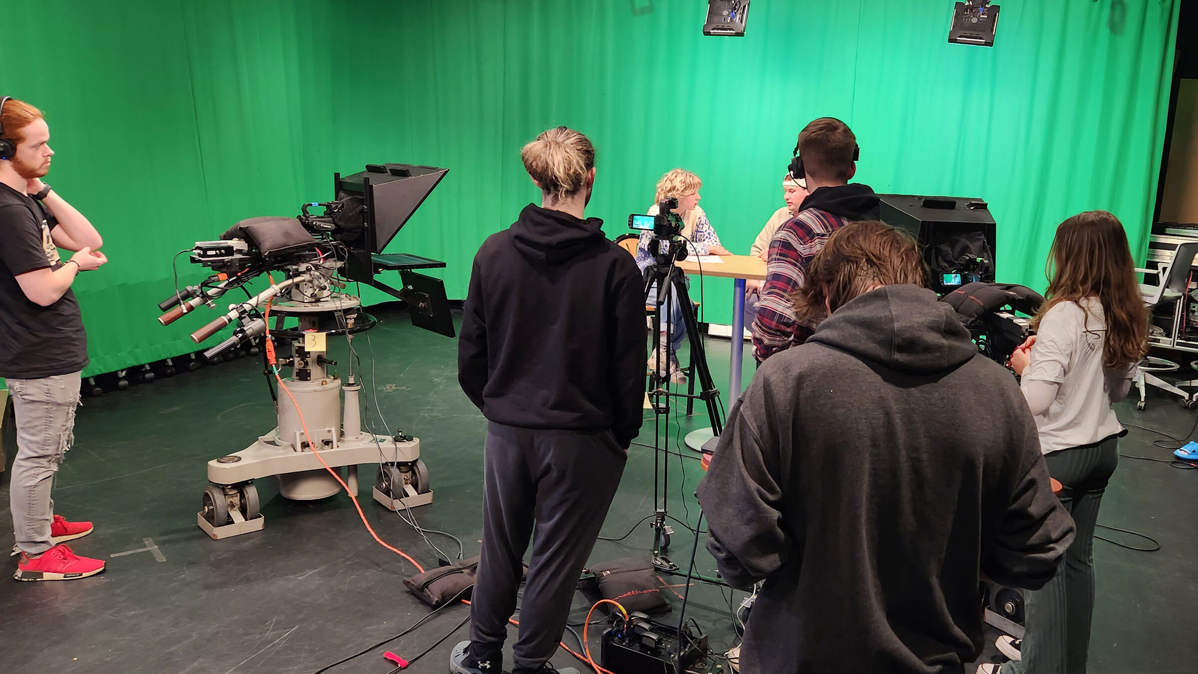 a group of students broadcasting in front of a green screen at Champlain's film stage with cameras and mics