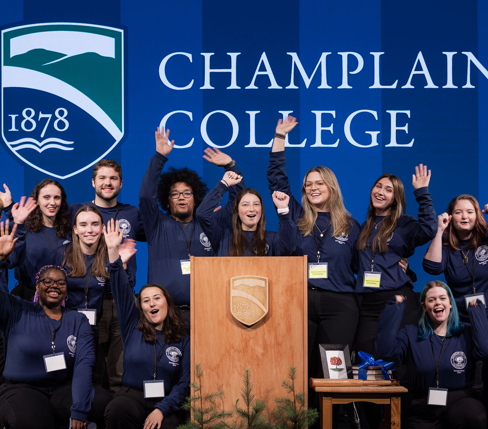A group of students pose enthusiastically with school spirit, in front of a Champlain College banner