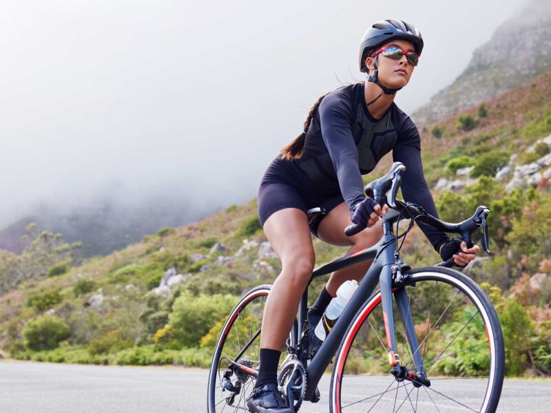 woman cycling on a mountain road where a helmet and sunglasses