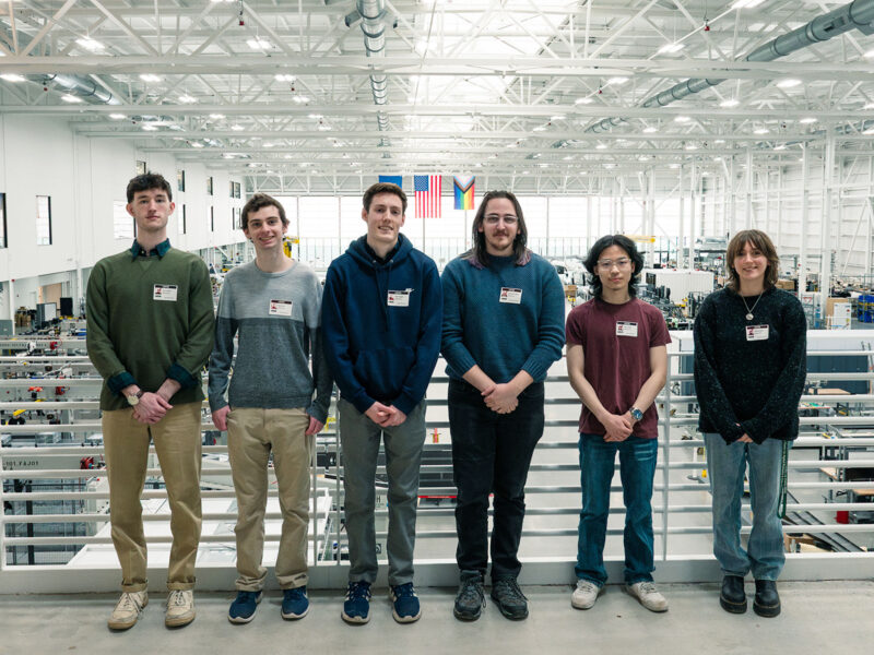 Six Champlain students pose in the hangar at BETA Technologies in Burlington, Vermont.