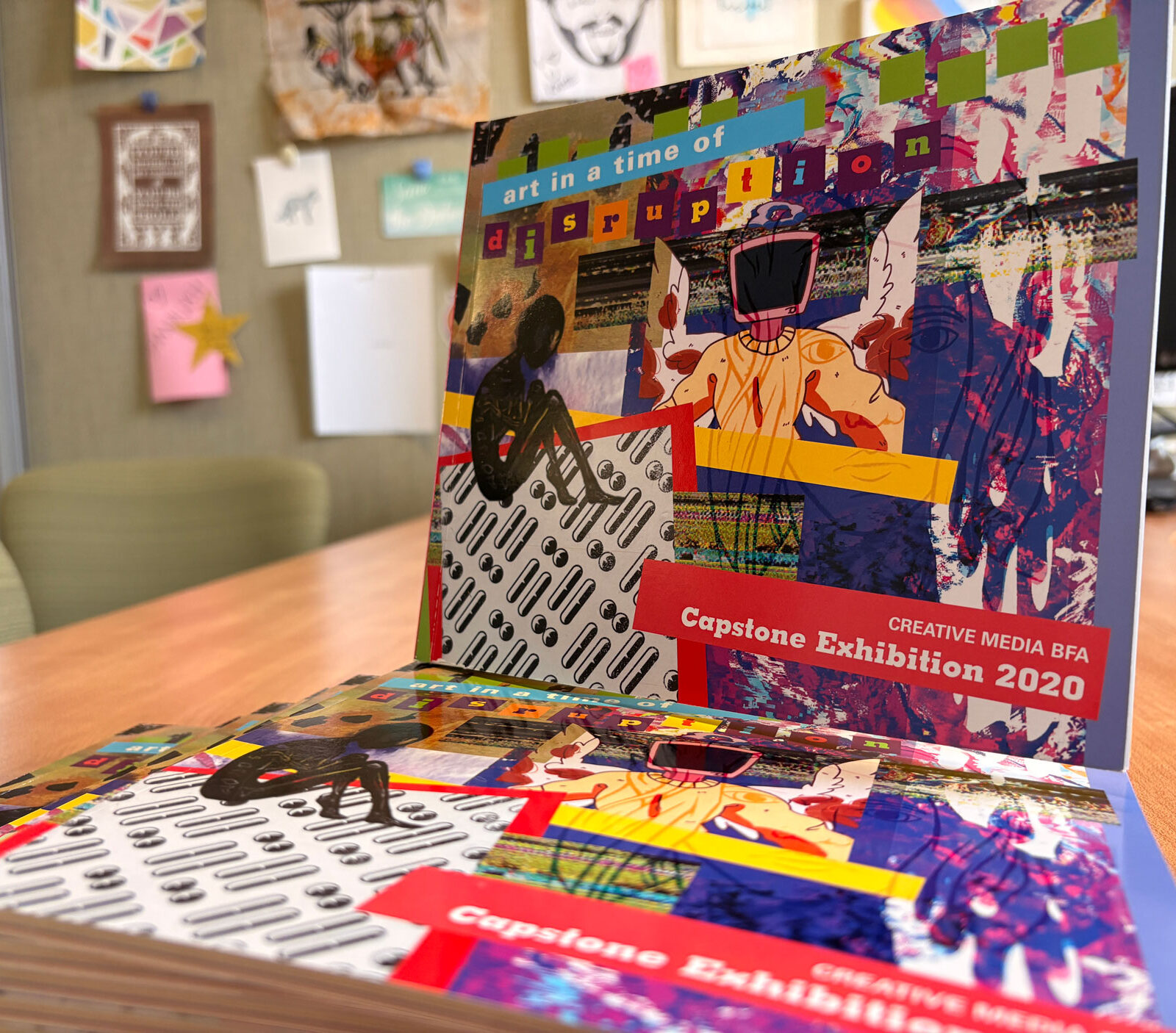 A stack of colorful books showcasing Creative Media student artwork
