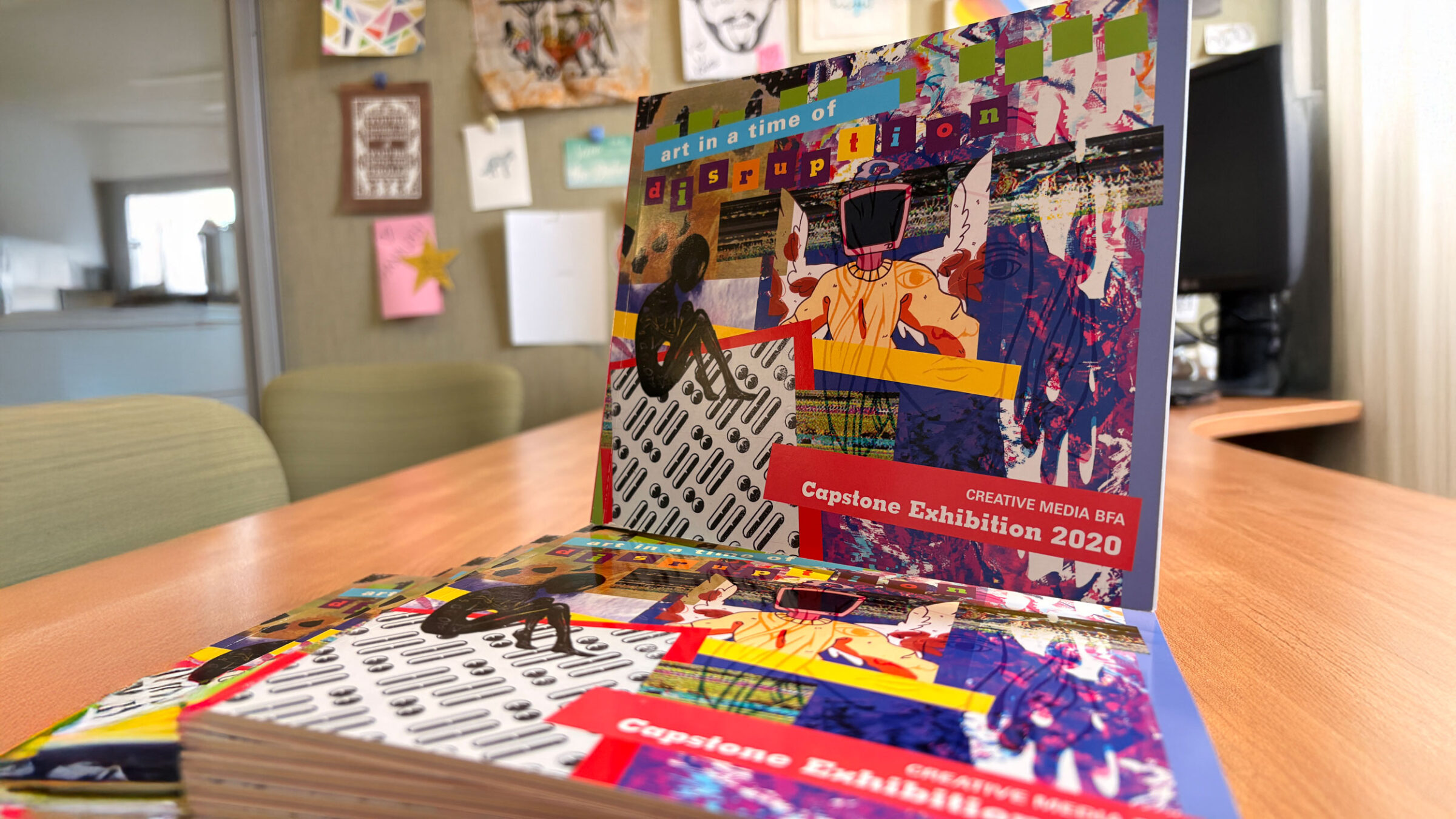 A stack of colorful books showcasing Creative Media student artwork