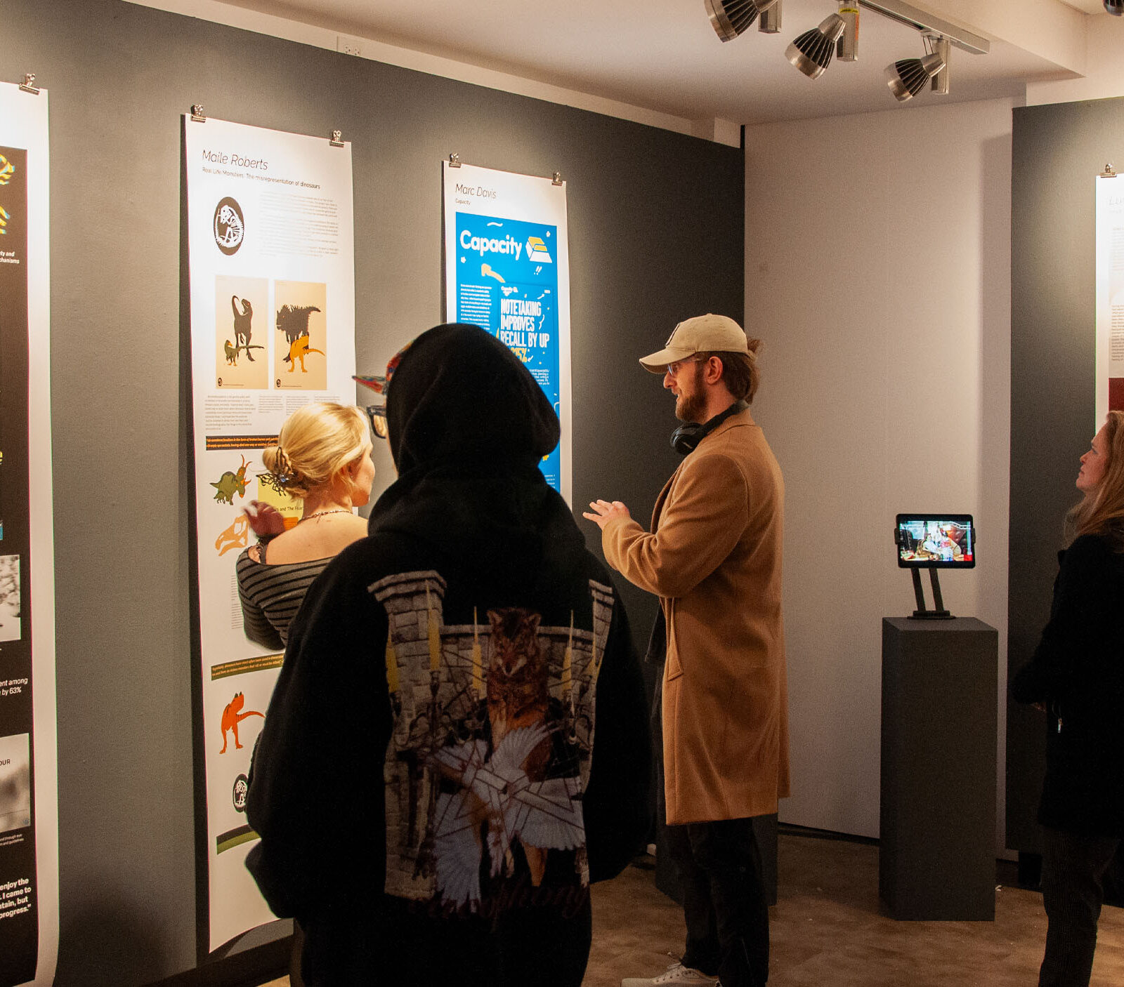 Students attending the graphic design senior capstone show in Champlain's art gallery looking at student work