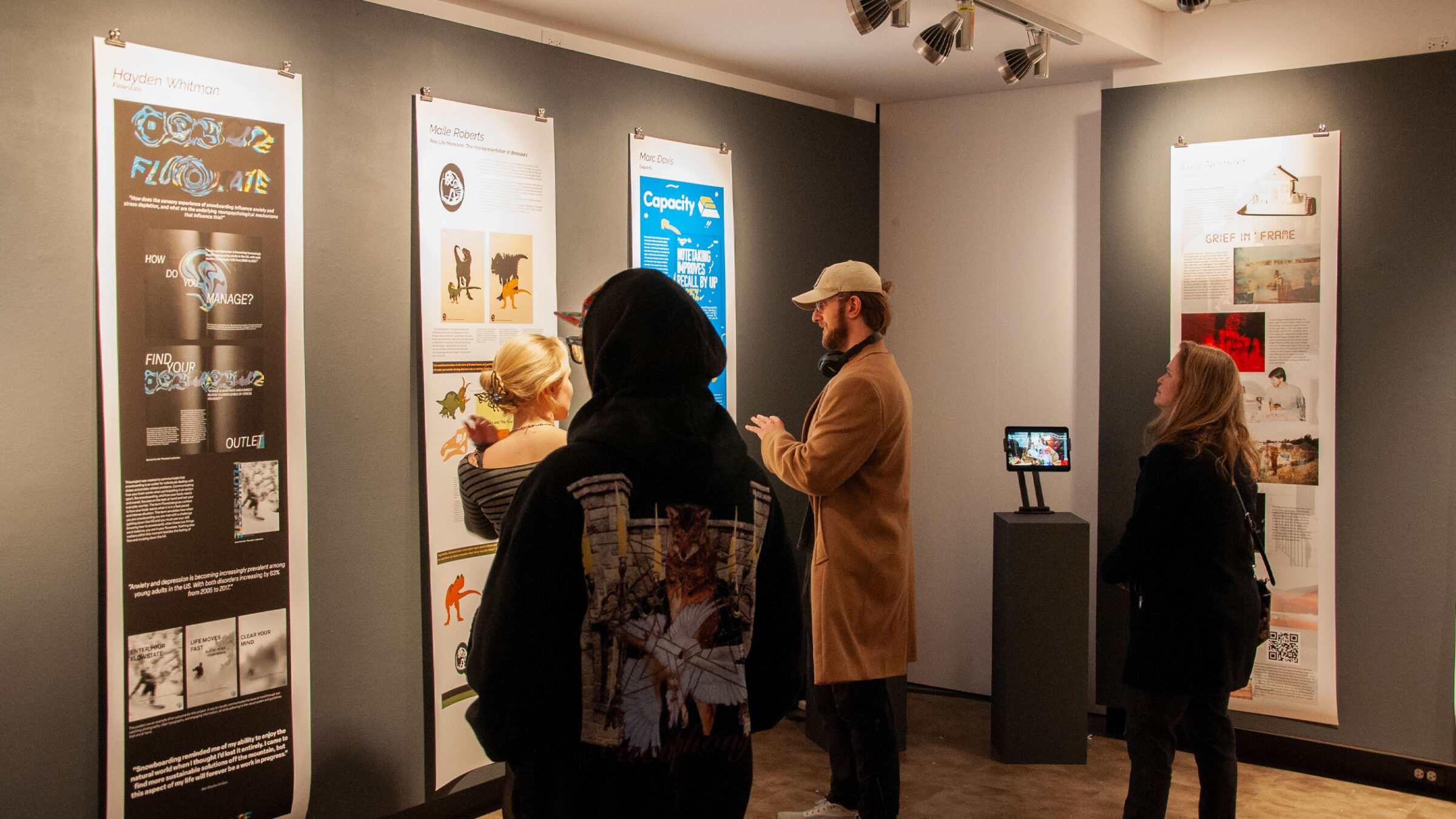 Students attending the graphic design senior capstone show in Champlain's art gallery looking at student work