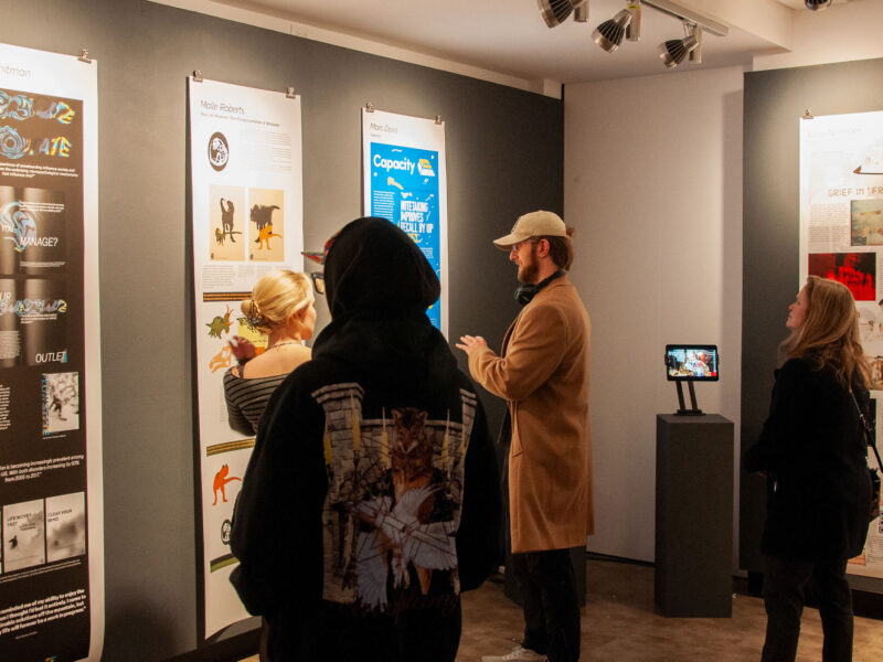 Students attending the graphic design senior capstone show in Champlain's art gallery looking at student work