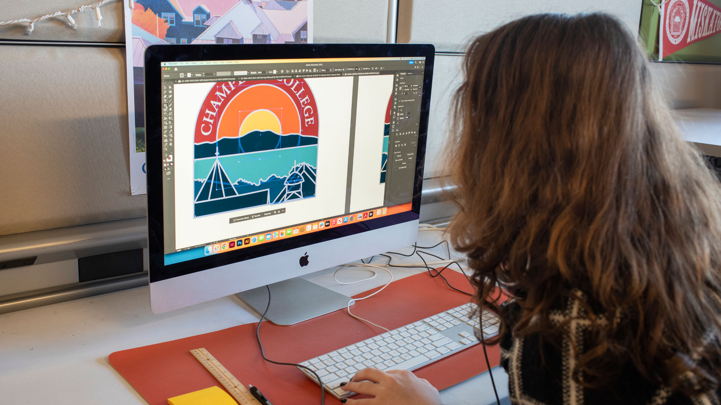 A student working on a brightly colored logo for Champlain college at a mac computer