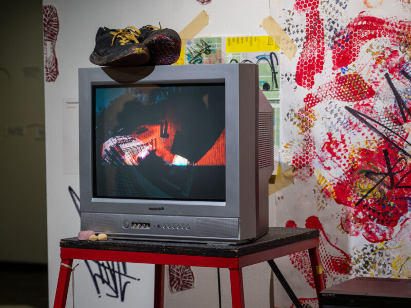 A creative media capstone gallery showcase with bright and vibrant colors featuring a tv and paint