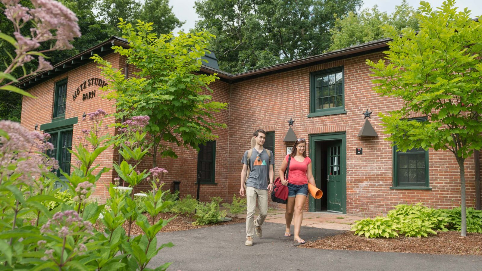 Two students walking out of a building on campus in the summer