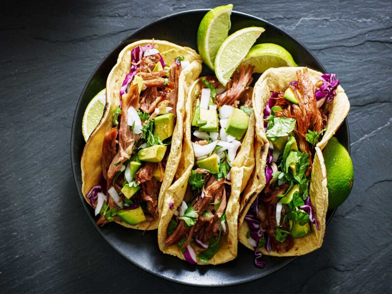 three tacos on a dark colored plate