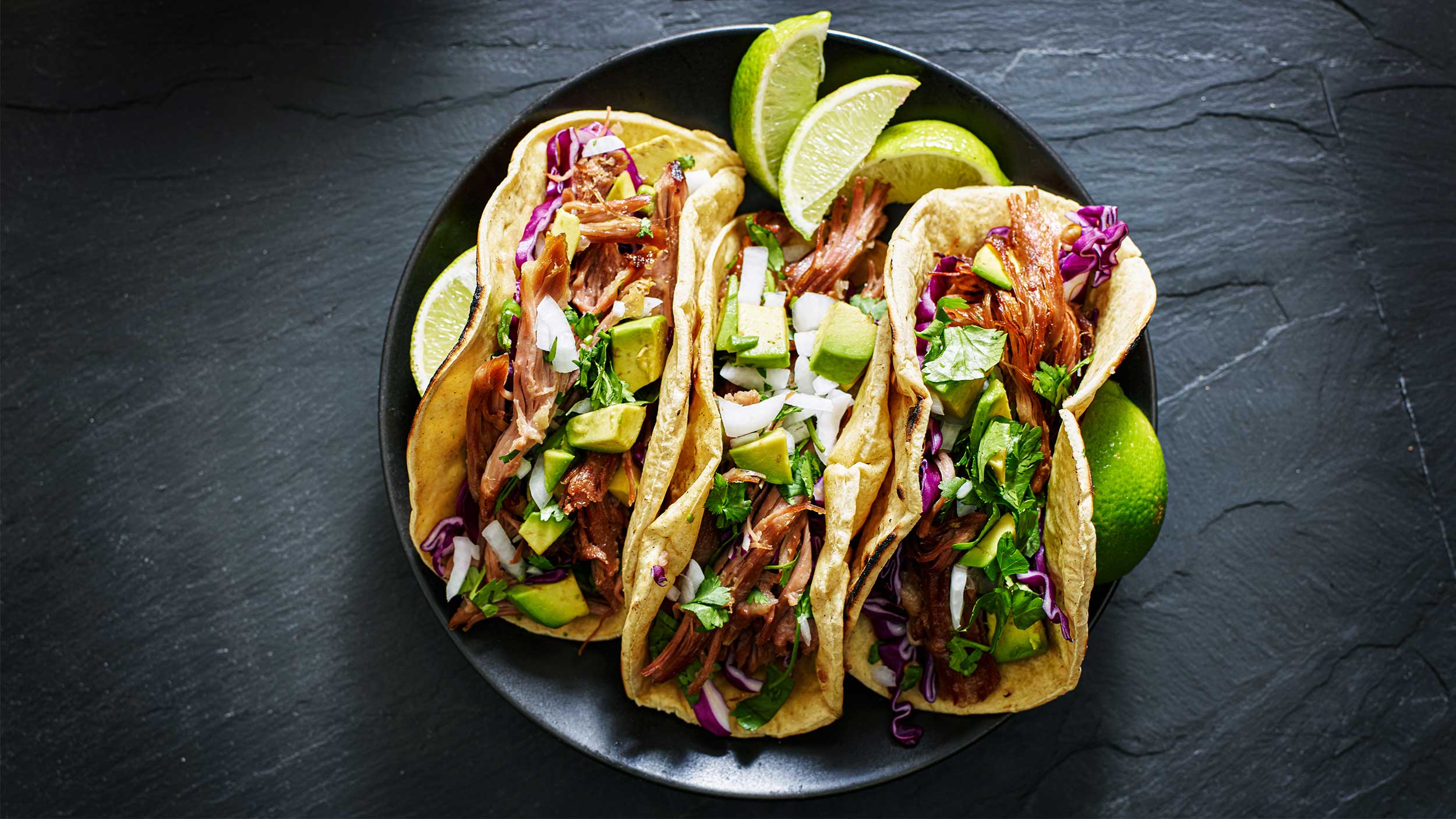three tacos on a dark colored plate