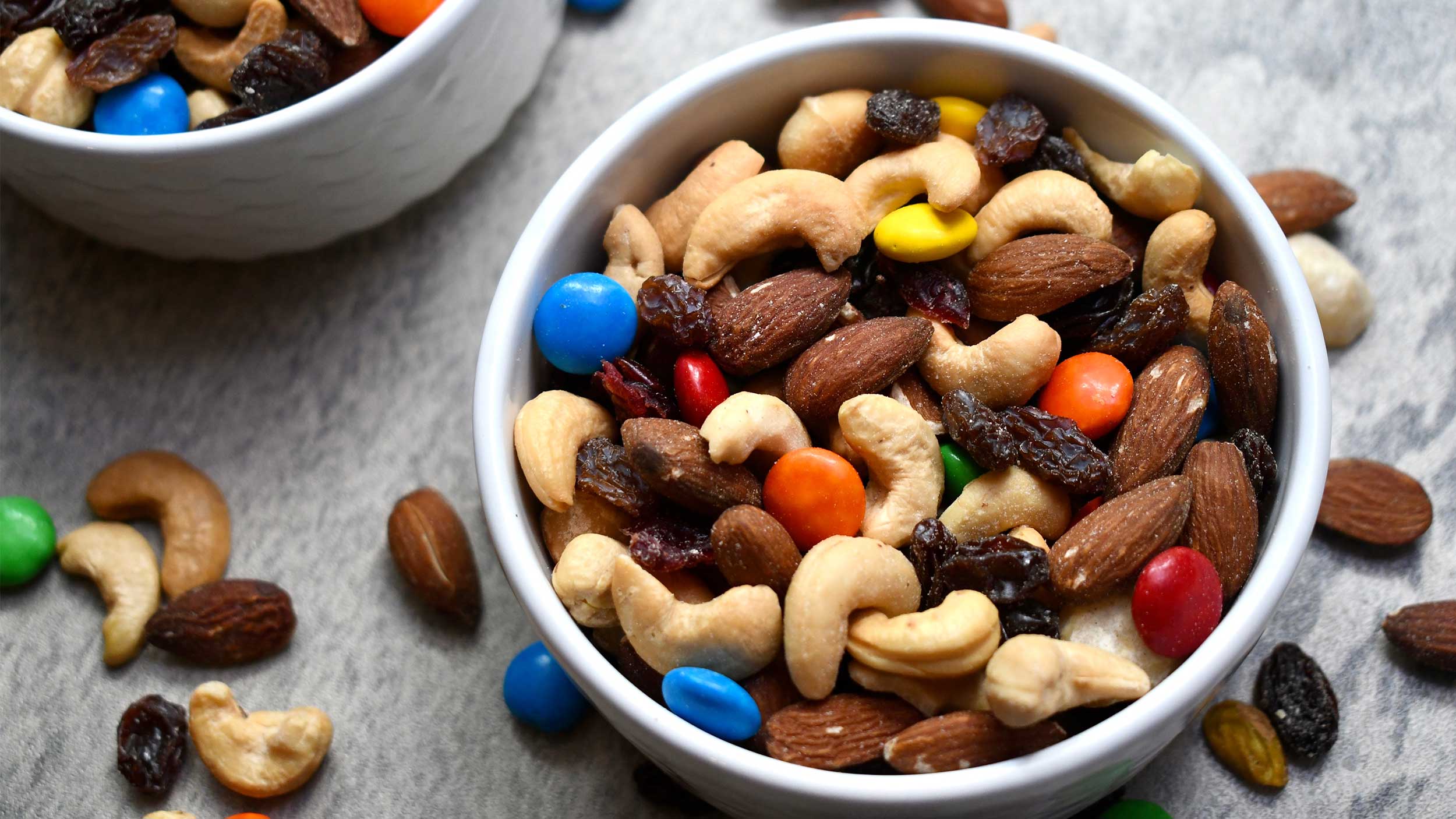 bowl of trail mix with mixed nuts, raisins, and chocolates