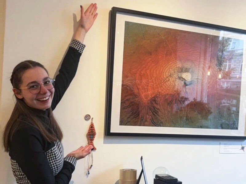 Alumni Vivi Torontali posing in front of artwork