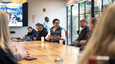 President Alex and others sitting at a table in Hula discussing business and entrepreneurship