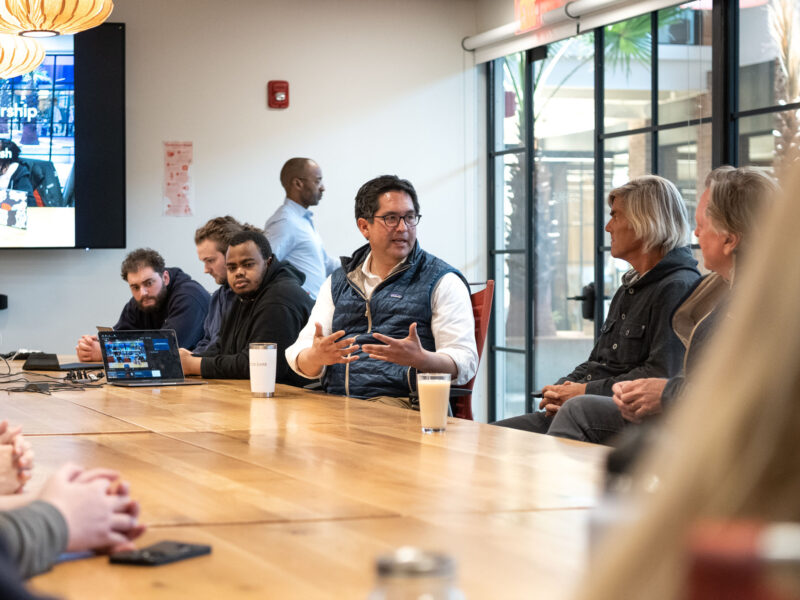 President Alex and others sitting at a table in Hula discussing business and entrepreneurship