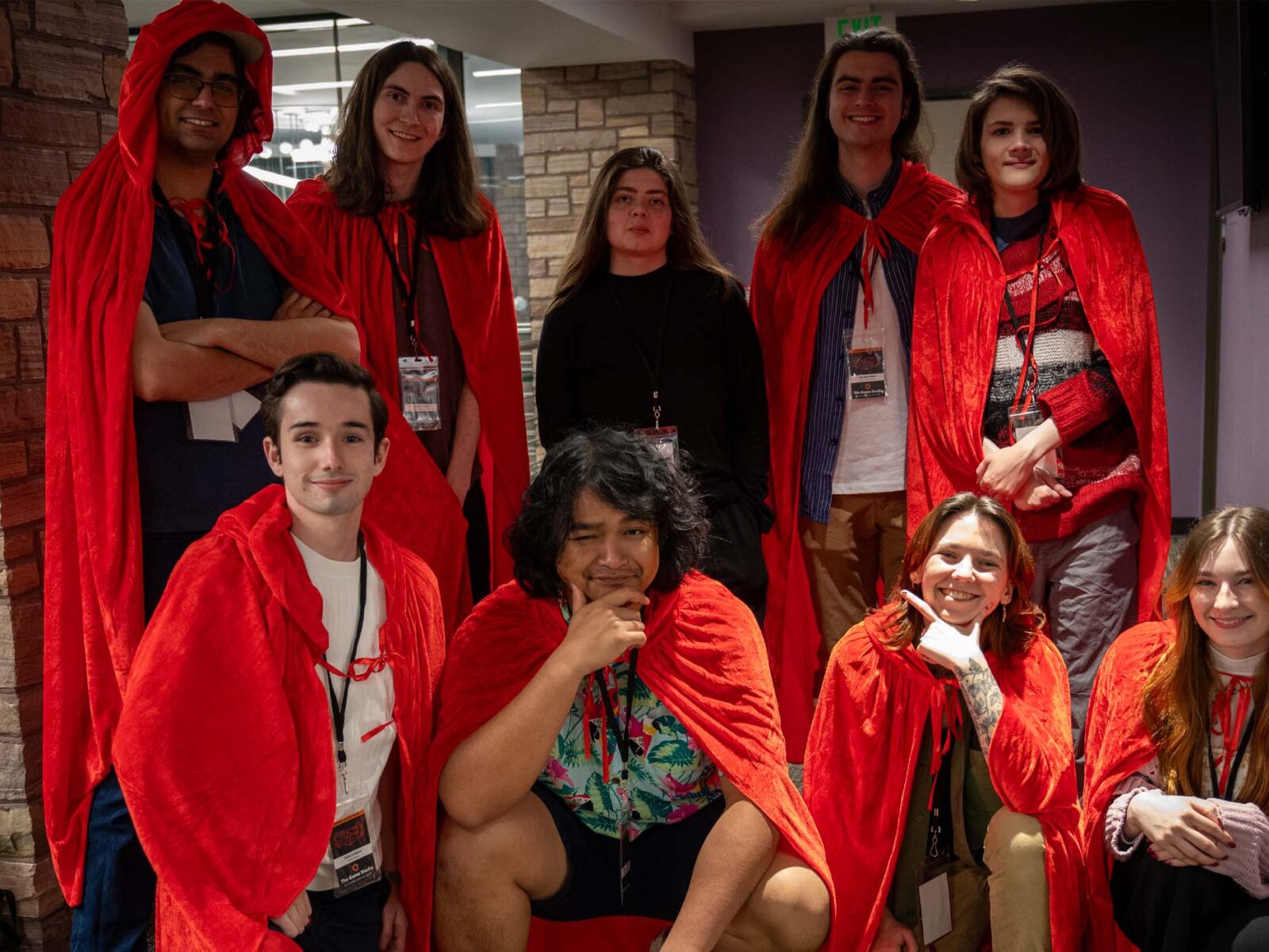 Red: Flame & Fable senior show team posing in the game studio wearing red cloaks
