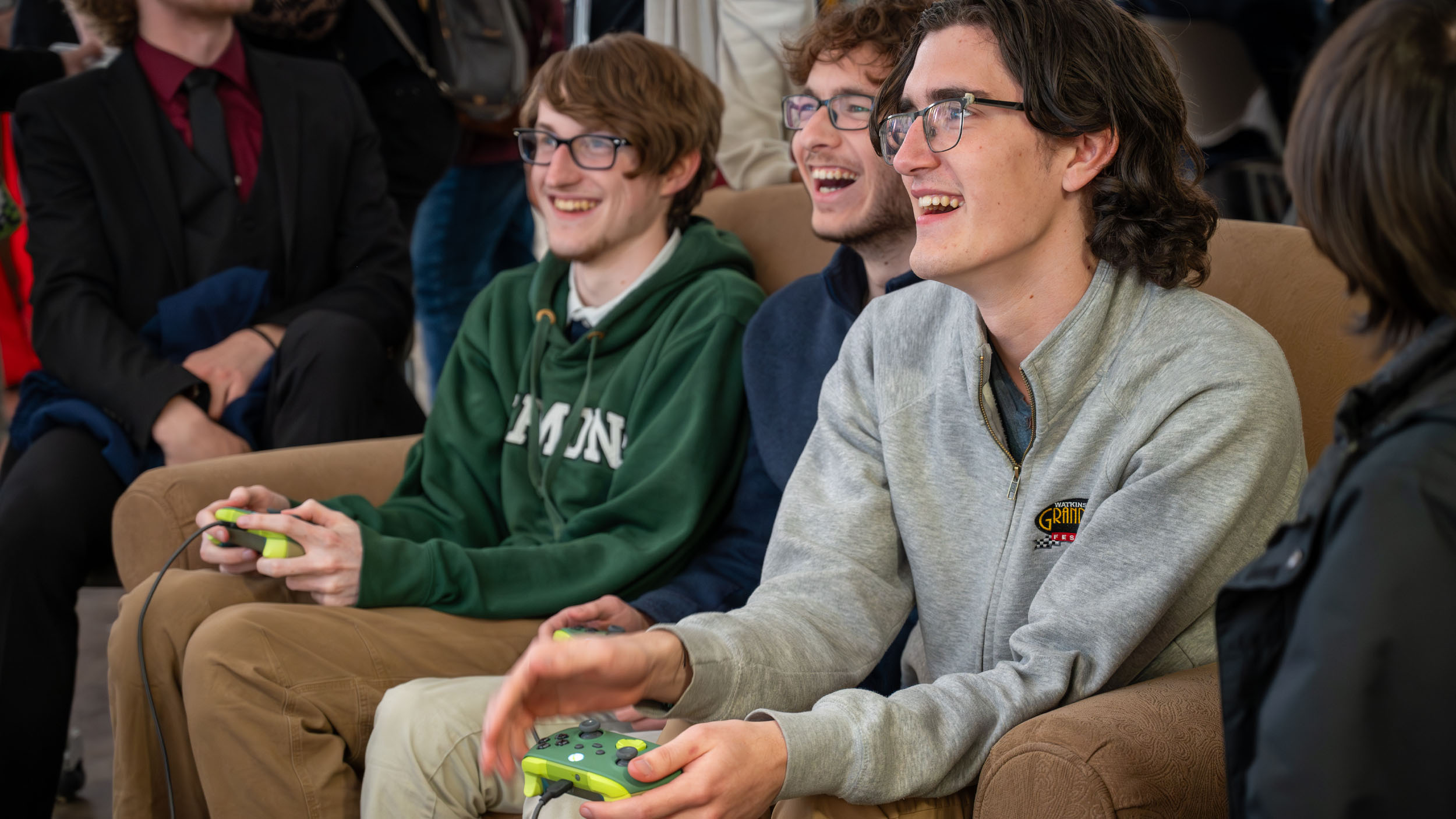 Students smiling and playing a game on controllers while sitting out a couch during Game Senior Show 2026
