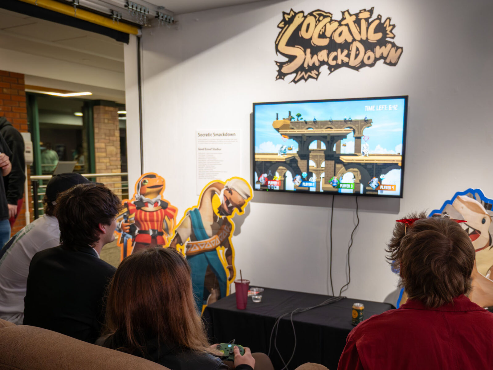 students playing a socratic smackdown while sitting on a couch in the art gallery during the game senior showcase gallery