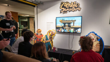 students playing a socratic smackdown while sitting on a couch in the art gallery during the game senior showcase gallery