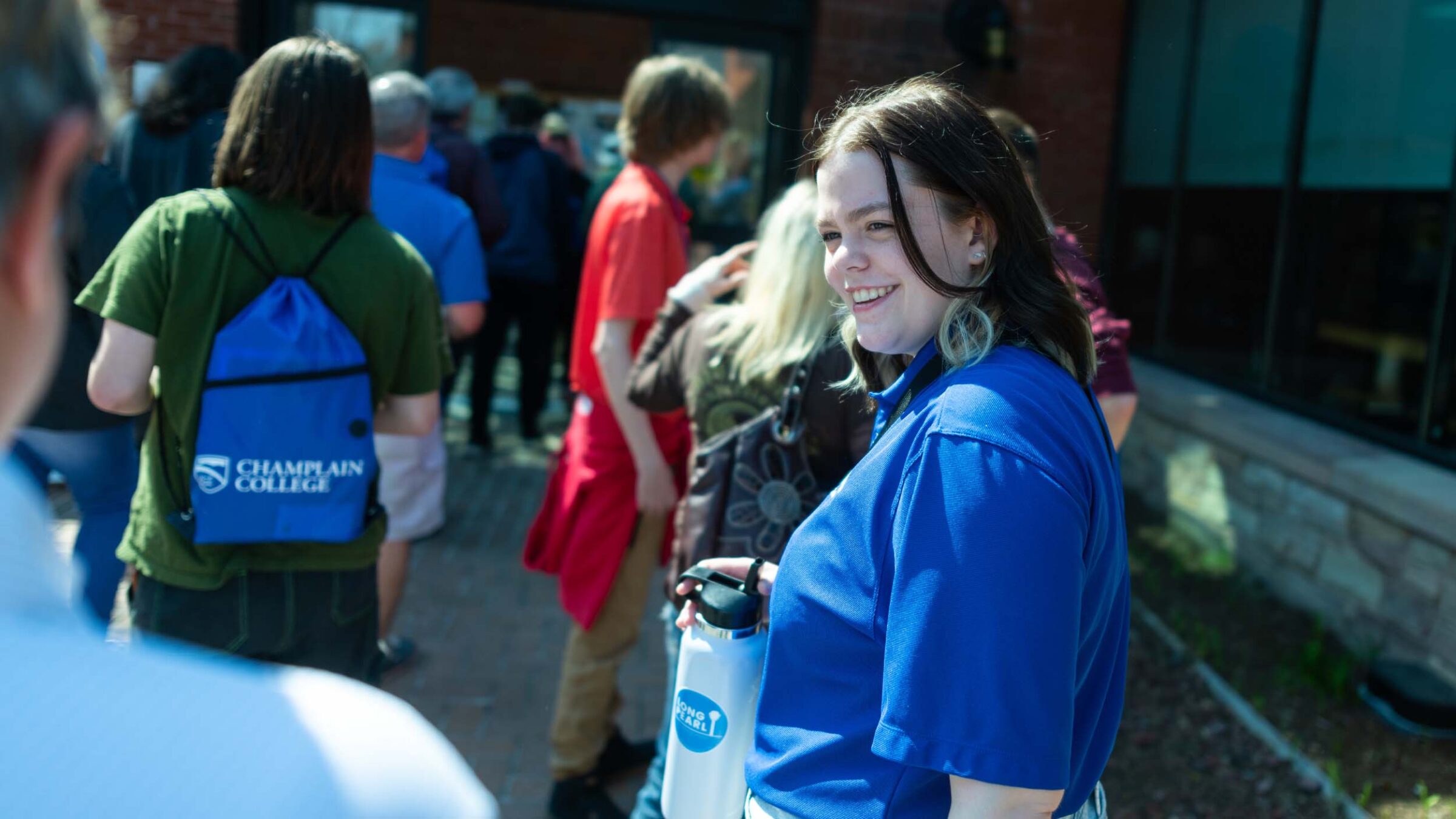 A student giving a campus tour to admitted students outside wearing blue