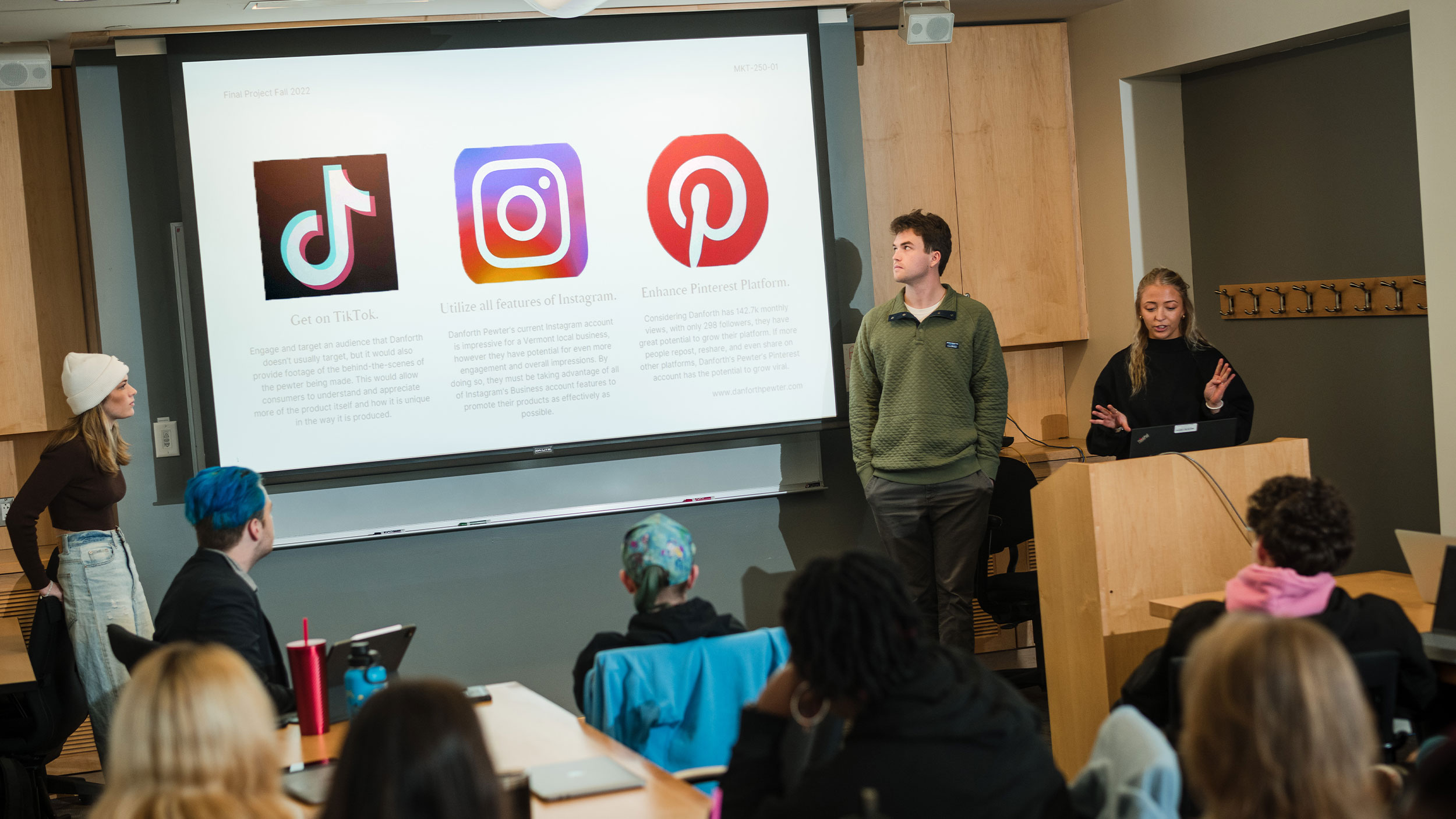 Marketing students present in front of a screen with social media icons