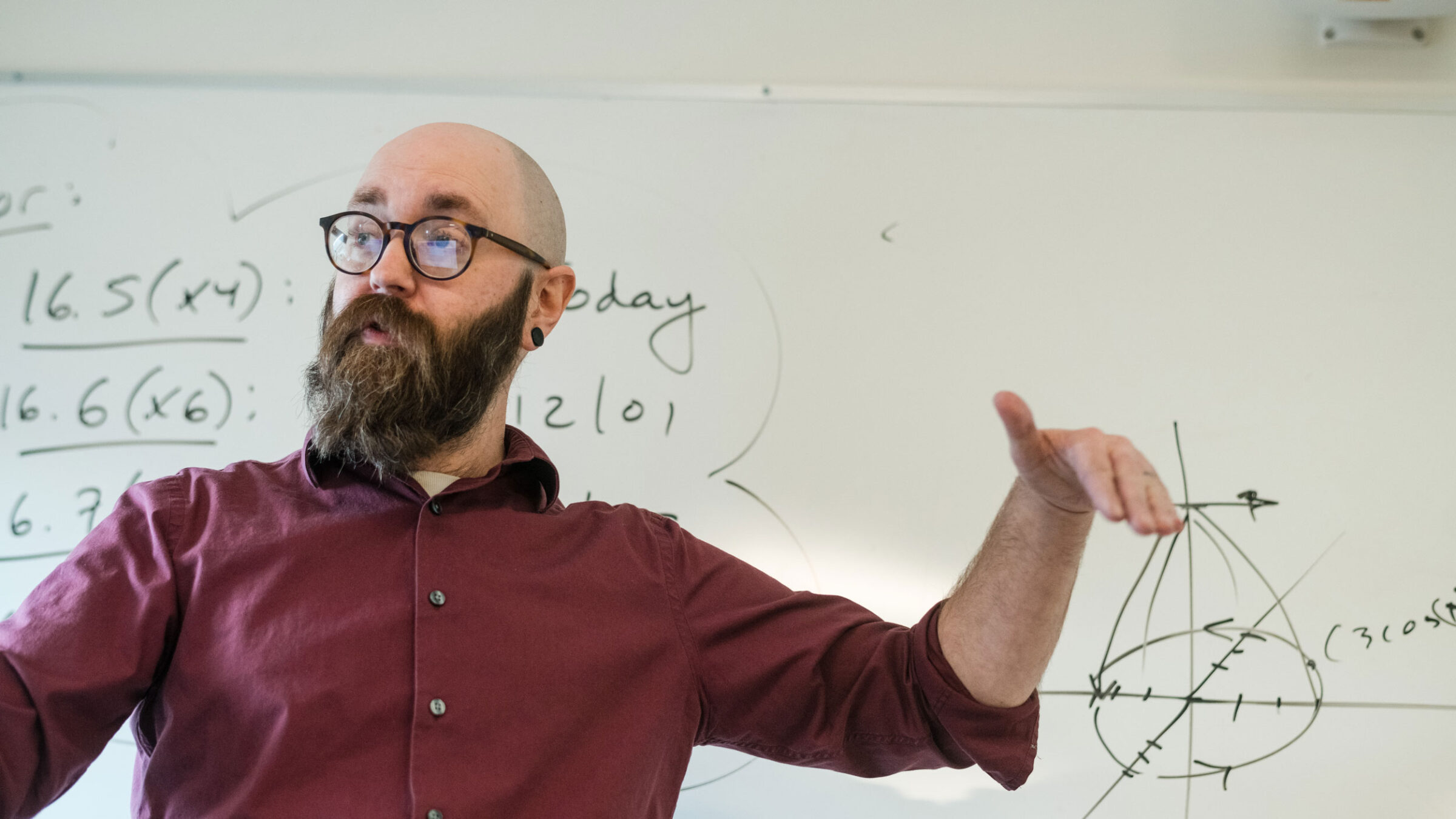 A Champlain professor teaching math to students on a whiteboard in class