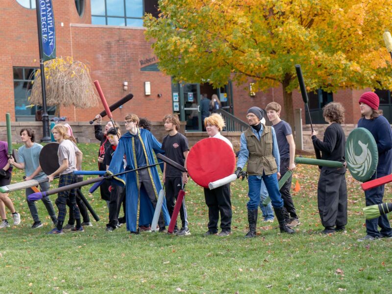 Hearthlight club group standing in line outside in the fall season on campus in front of the library