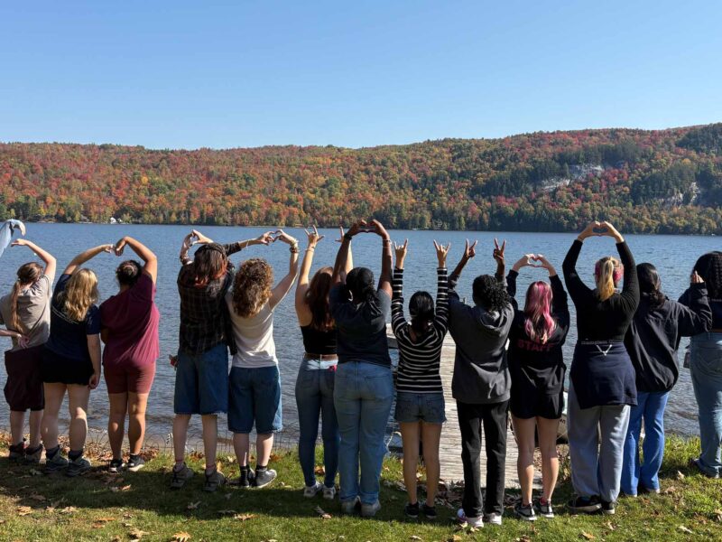 Student's from the Women & Gender Center's retreat posing for a photo in front of a Lake in Vermont