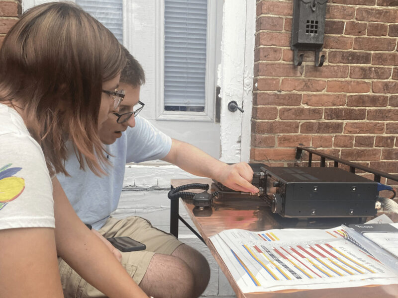 Two people testing an old radio outside