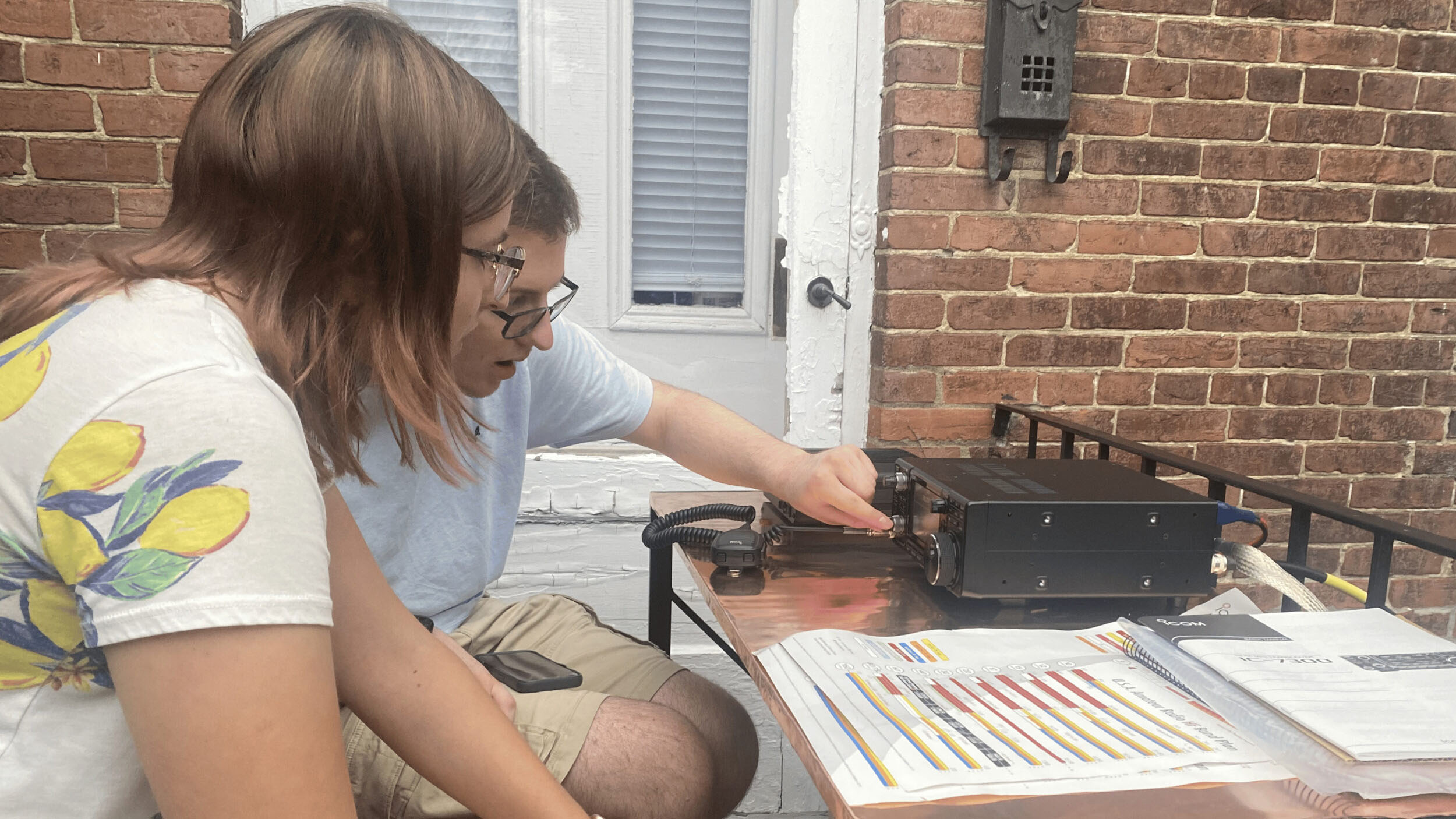 Two people testing an old radio outside