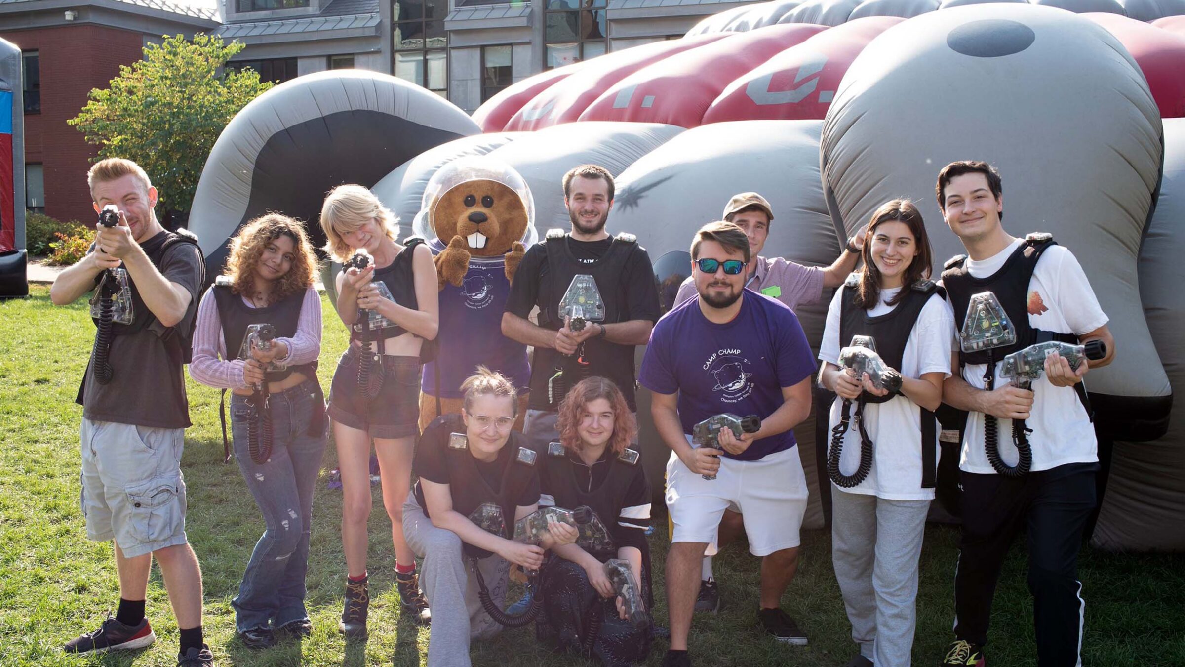 Chauncey and students posing for a photo in front of a blow up bounce house wearing greys and purples