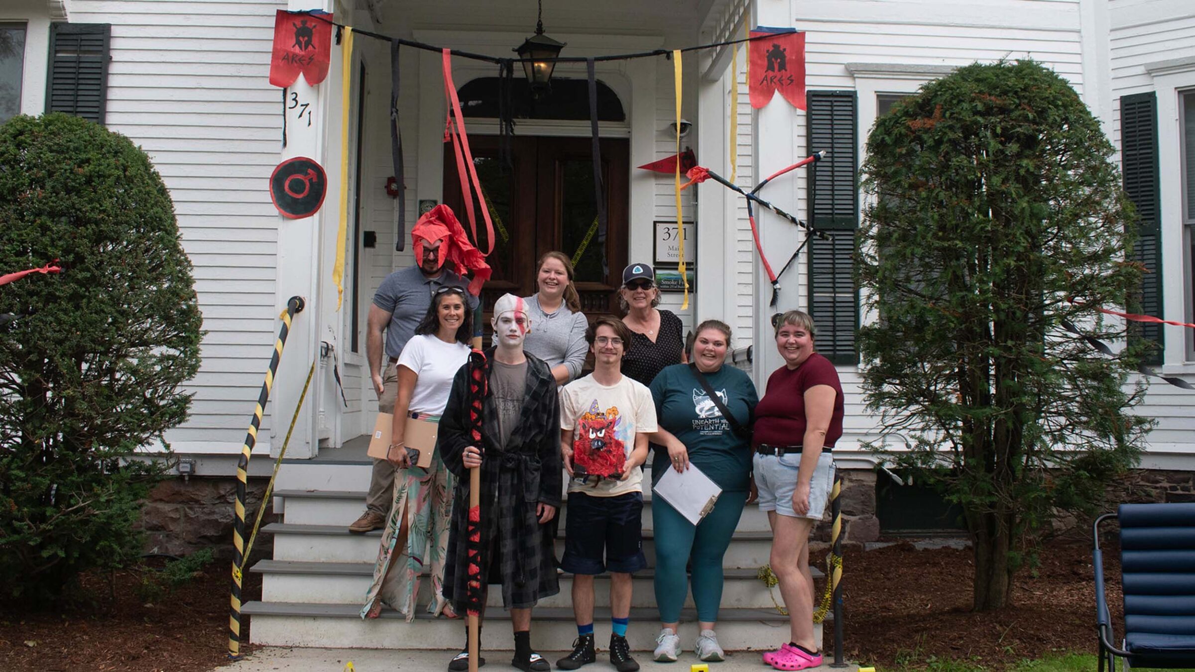 A group posing in front of their decorated stoop done in the theme of Aries with reds, blacks, and yellows.