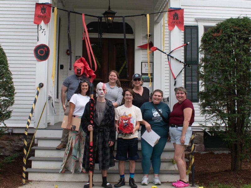 A group posing in front of their decorated stoop done in the theme of Aries with reds, blacks, and yellows.