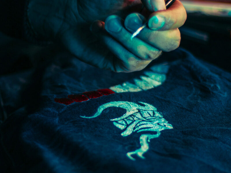 A stock image of someone using bleach to paint a design onto a dark colored shirt.