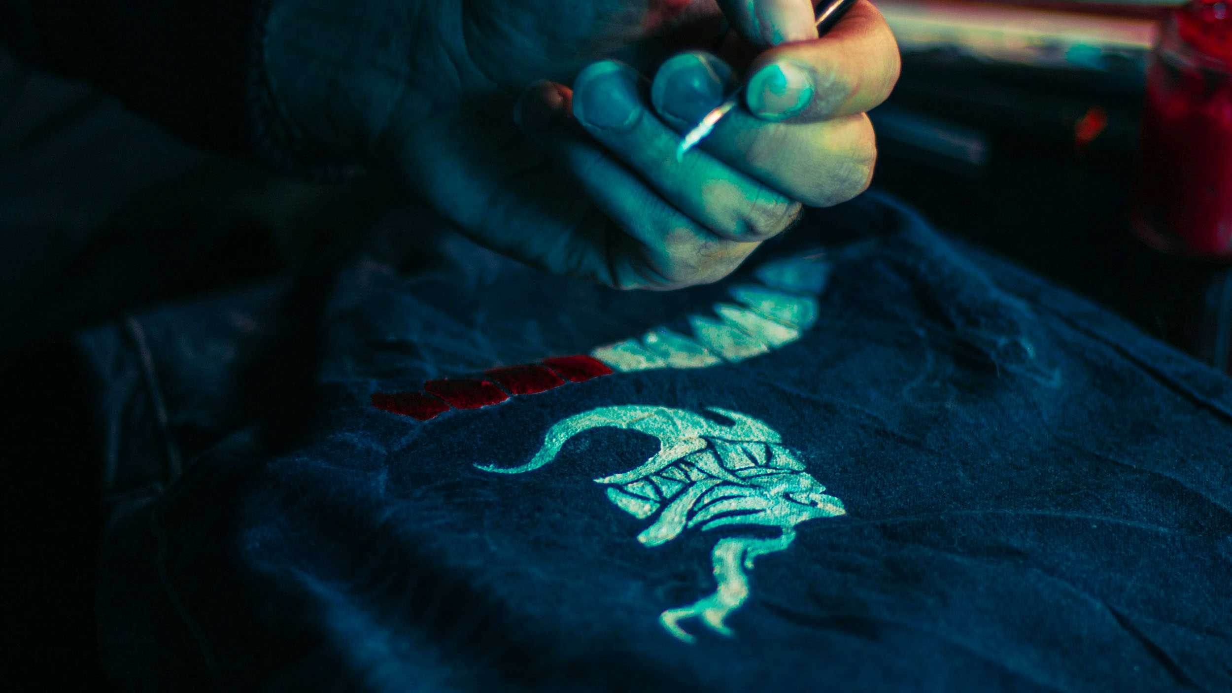 A stock image of someone using bleach to paint a design onto a dark colored shirt.
