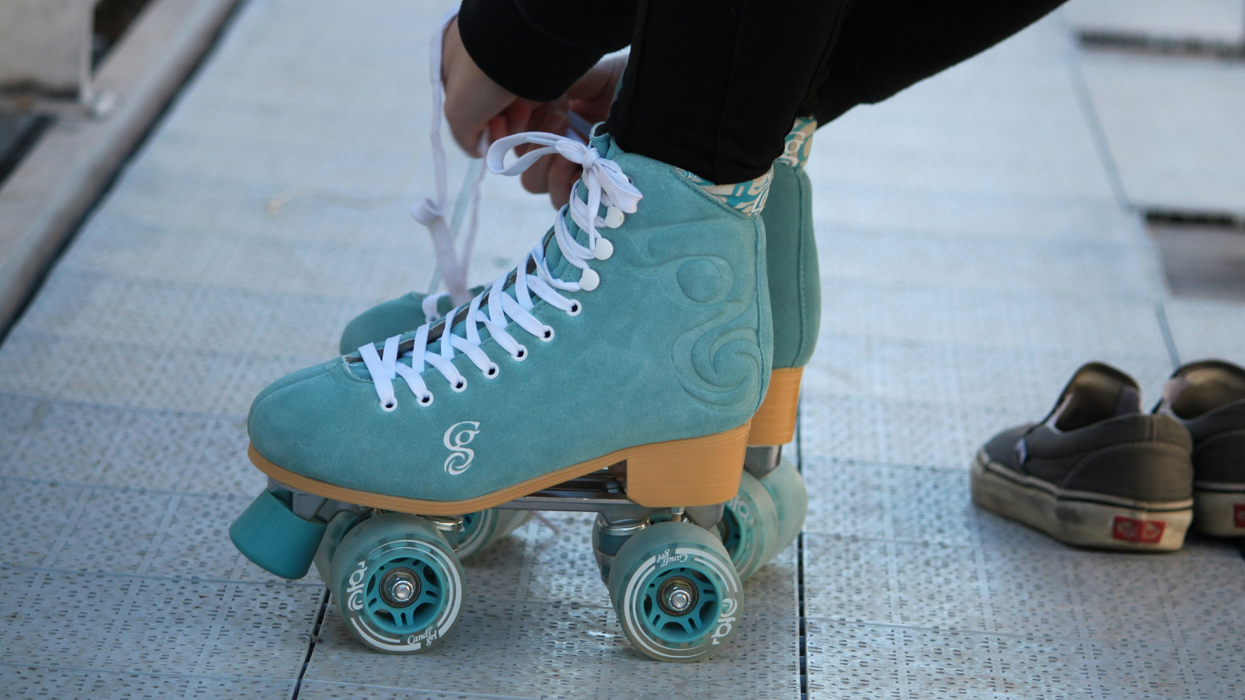 A person tying blue and orange roller skates