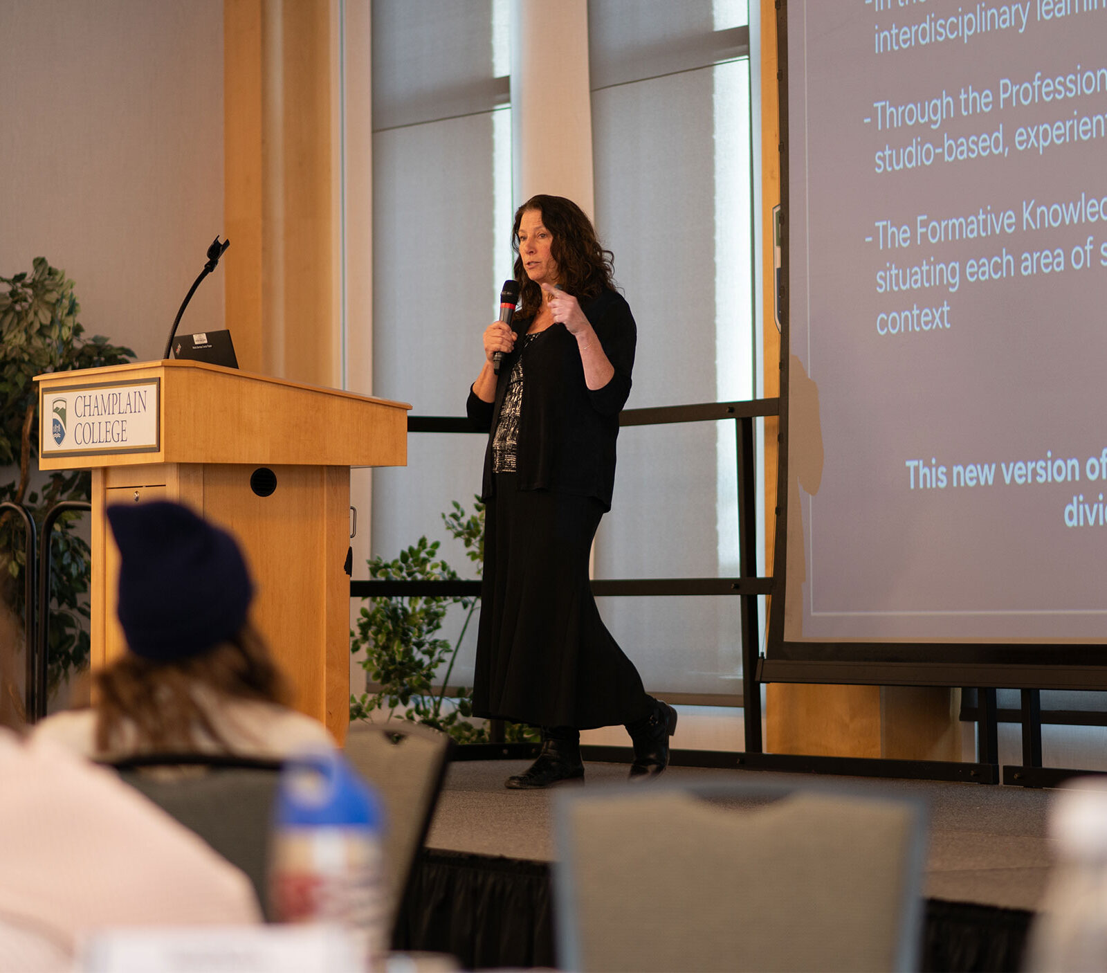 professor stands on stage with microphone in hand