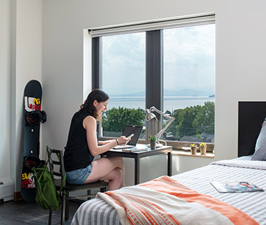 student sitting at desk in dorm with lake view