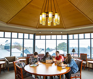 students sitting at round table in room with view
