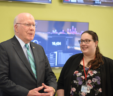 Senator Patrick Leahy and a student speak in front of screens in The Leahy Center
