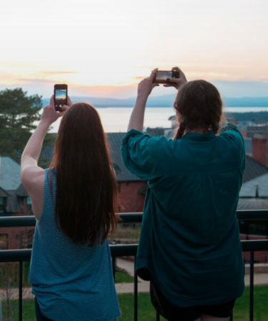 Students capturing photos with their phones of the sunset over Lake Champlain