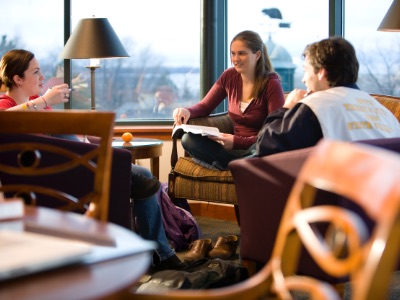Three Champlain College students studying in front of large windows in the Miller Information Commons, the Champlain College library in Burlington, Vermont.