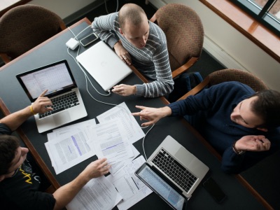 Overhead shot of 3 students sitting around a conference table, collaborating